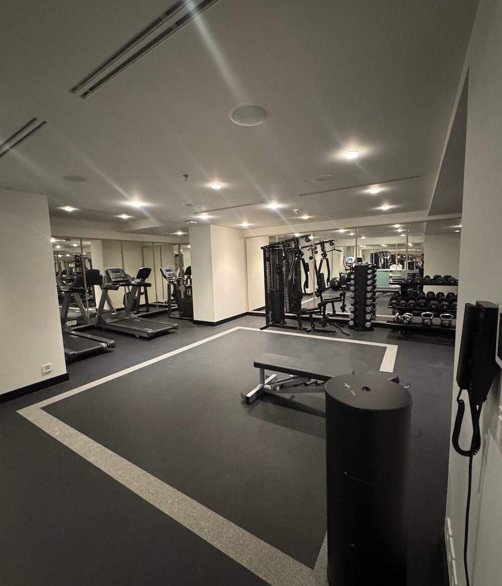 a photo of a gym with equipment that includes treadmills, free weights, kettlebells, a workout bench and all-in-one full-body workout machine.